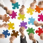 Hände halten Puzzleteile in der Hand